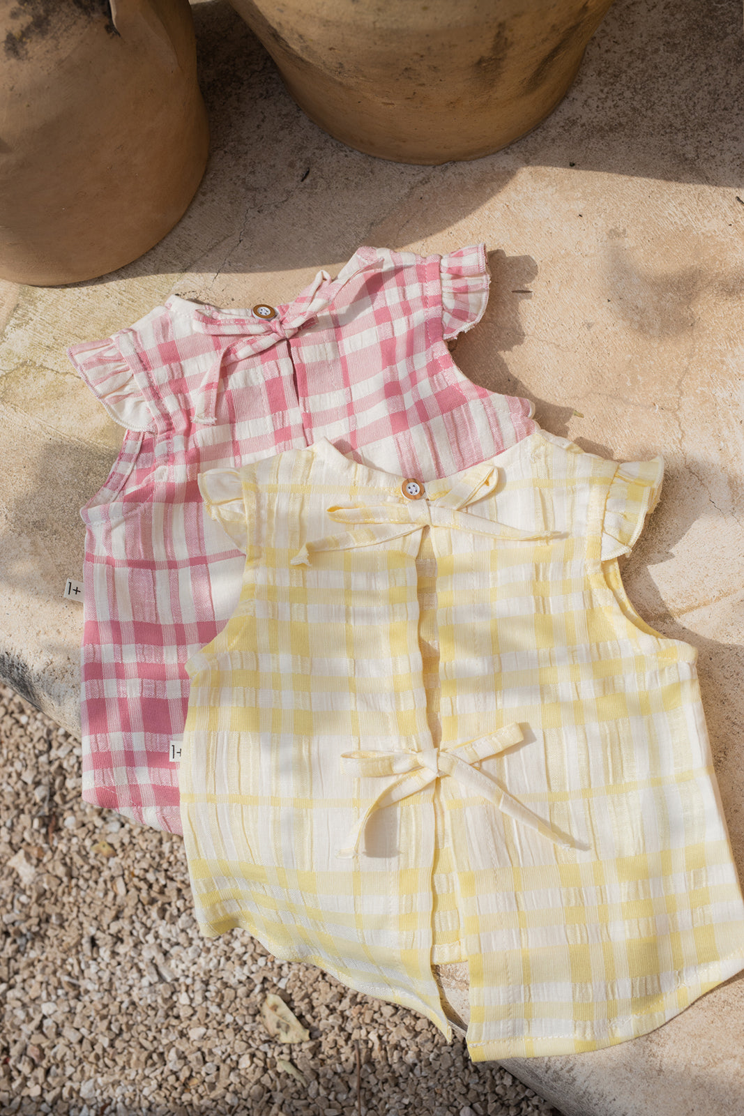 1+ in the family Ferrosa lemon Produktbild, drapiert mit der gleichen Bluse in strawberry, auf Steinboden liegend