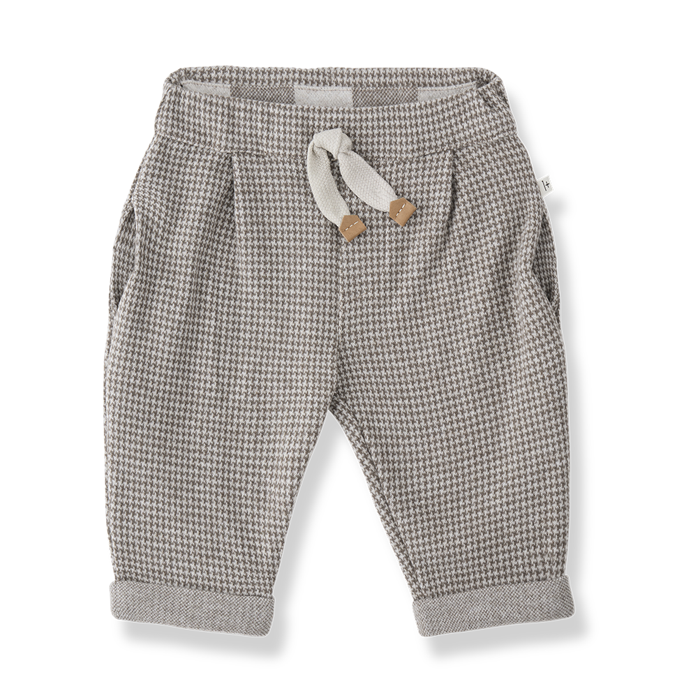 beigefarbene Hose für Babys und Kleinkinder mit dunkelbraunem Hahnentritt-Muster, weichem Gummibund, seitlichen Eingriffstaschen und umgeschlagenen Hosenbeinen. Produktbild, Ansicht von vorne. 