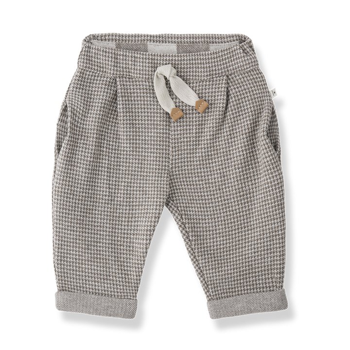 beigefarbene Hose für Babys und Kleinkinder mit dunkelbraunem Hahnentritt-Muster, weichem Gummibund, seitlichen Eingriffstaschen und umgeschlagenen Hosenbeinen. Produktbild, Ansicht von vorne. 
