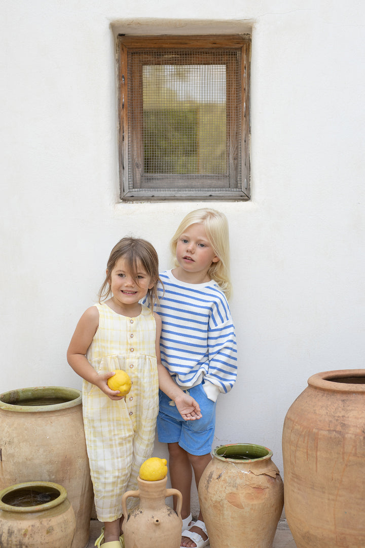 1+ in the family Marroig ultramarine getragen von einem Kind vor einer Hauswand, Ansicht von vorne 