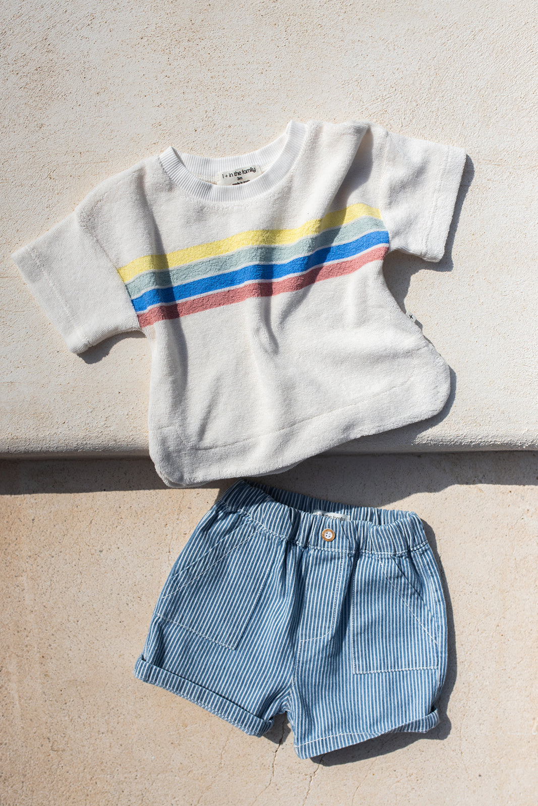 1+ in the family Alocs off-white Porduktbild, drapiert mit der Shorts Andratx auf Steinboden liegend