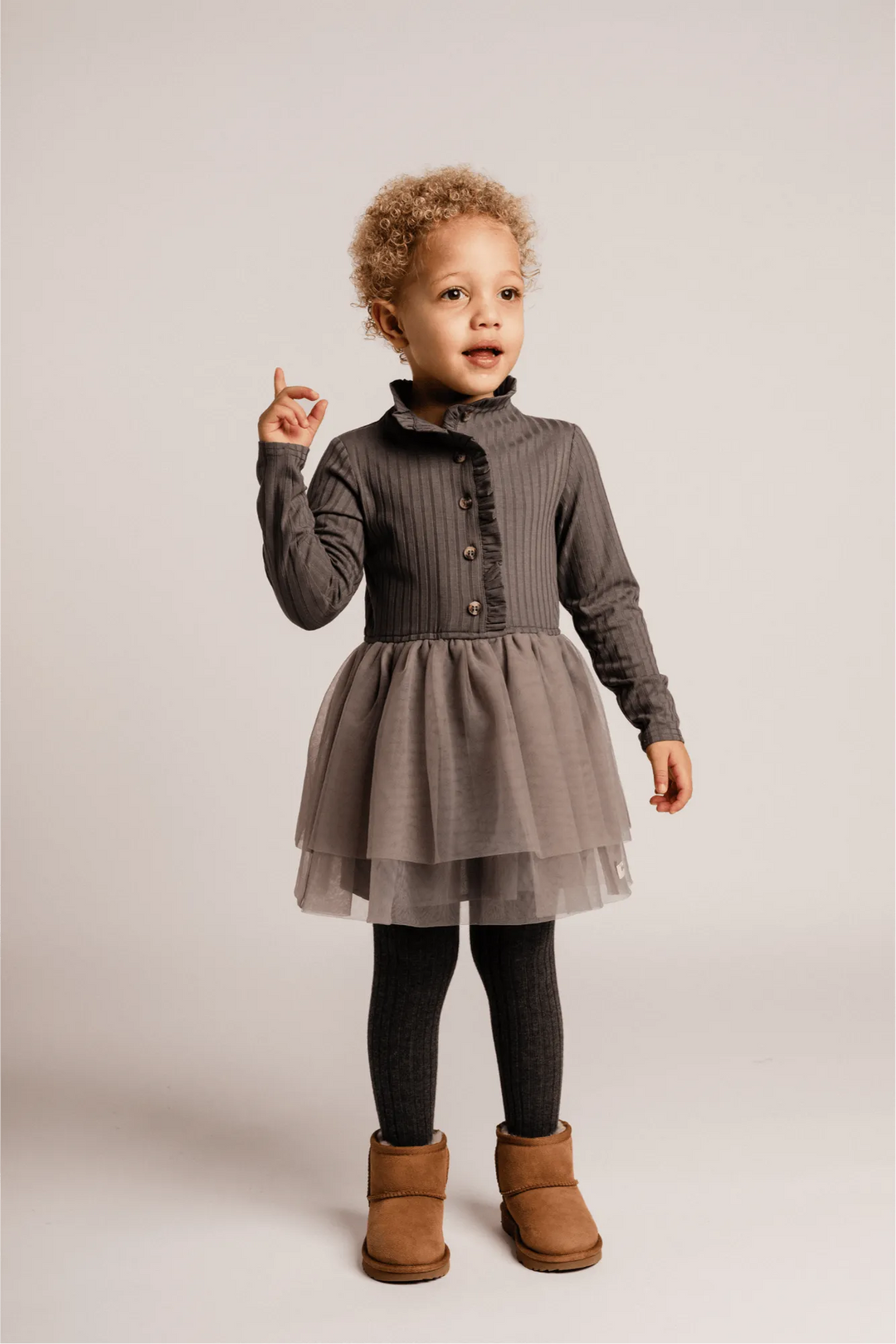 graues Kleid aus Baumwolle für Mädchen mit geripptem Oberteil, gerüschtem Kragen und Knopfleiste, langem Arm und Tüllrock, hier getragen von einem Mädchen vor weißem Hintergrund