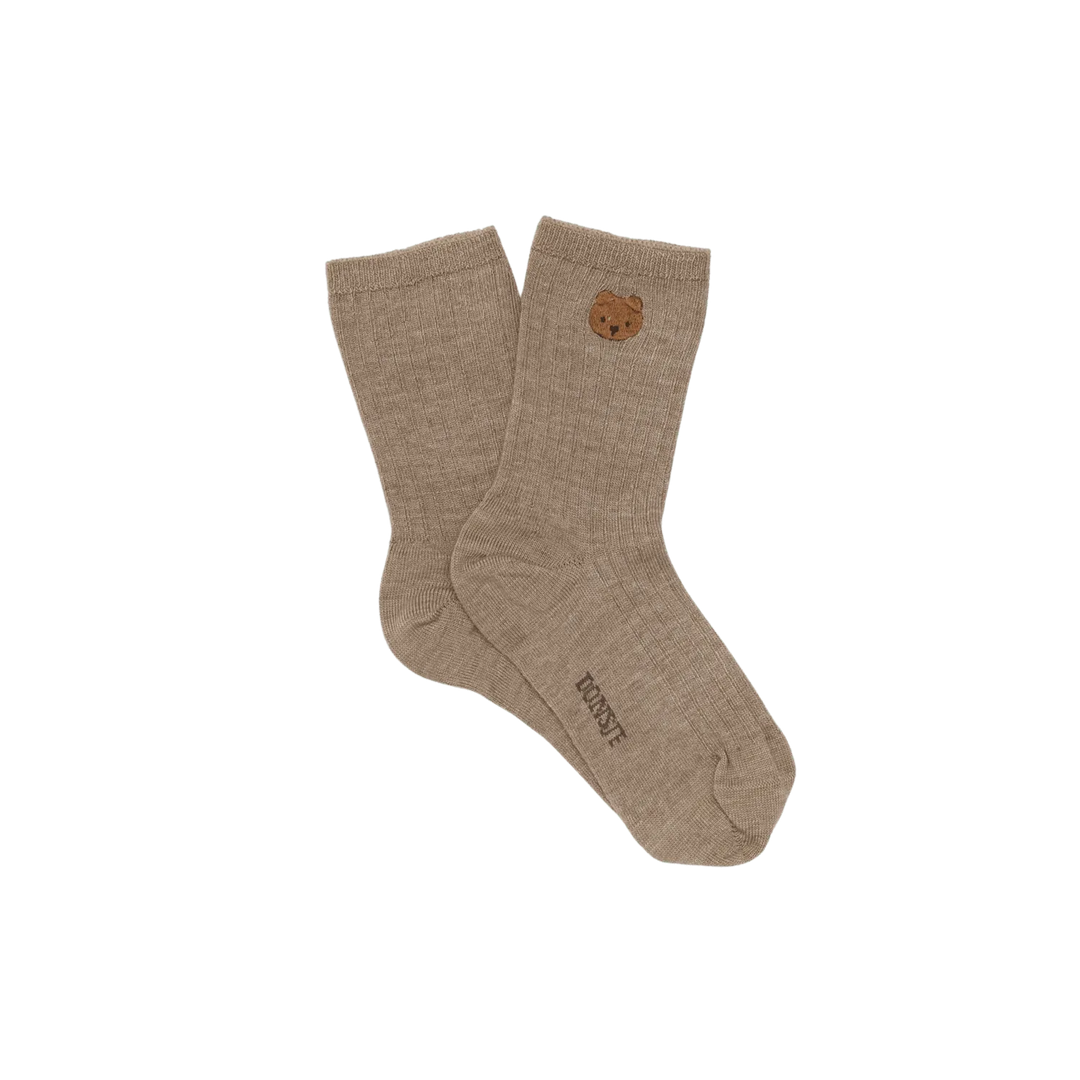braune Socken für Babys und Kleinkinder aus Bio-Baumwolle mit dem Donsje Bärengesicht, aufgestickt unterhalb des Saums und eingewebtem Logo von Donsje auf der Sohle 