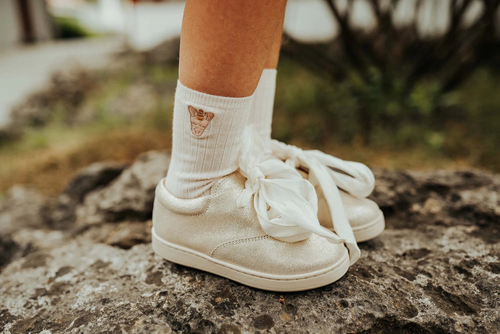 Donsje Bell Socks Unicorn soft powder getragen von einem Kind in Schuhen steckend mit Fokus auf das aufgenähte Einhorn-Gesicht