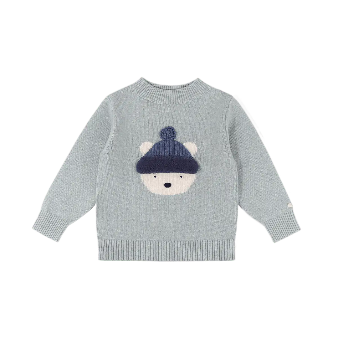 hellblauer Pullover aus 100% Merinowolle für Babys, Kleinkinder und Kinder mit eingestricktem Eisbärengesicht mit blauer Pudelmütze. Gerippte Bündchen an den Ärmeln und am Saum. Gerippter Rundhalsausschnitt. Produktbild, Ansicht von vorne. 