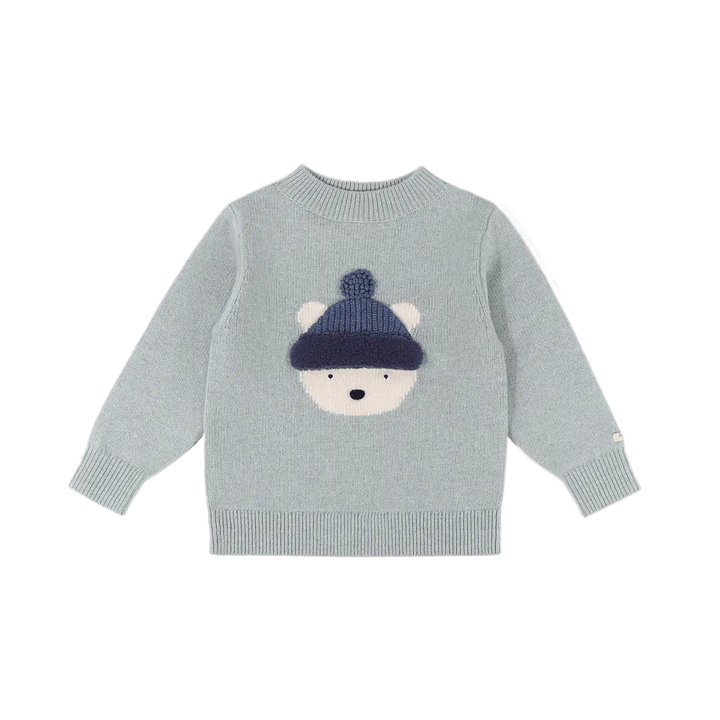 hellblauer Pullover aus 100% Merinowolle für Babys, Kleinkinder und Kinder mit eingestricktem Eisbärengesicht mit blauer Pudelmütze. Gerippte Bündchen an den Ärmeln und am Saum. Gerippter Rundhalsausschnitt. Produktbild, Ansicht von vorne. 