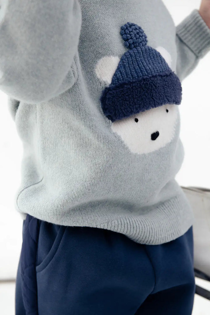 Donsje Denn Merino Wool Sweater Polar Bear cloud blue melange getragen von einem Kind, Detailansicht Eisbären-Gesicht, Ansicht von der Seite. 