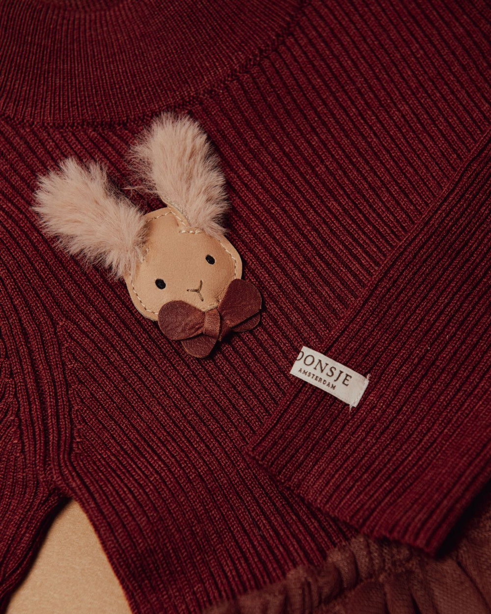 Donsje Festie Clip Fluffy Bunny light rust leather angebracht an dem Donsje Lotus Kleid in rustic brown, Detailansicht. 
