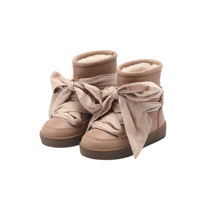 rosé-braune Lederstiefel mit halbhohem Schaft für Mädchen mit warmem Futter aus Schafswolle und rutschfester Gummi-Sohle. Verziert von voluminösen Baumwollbändern, die wie Schnürsenkel auf den Stiefeln angebracht sind und eine große Schleife bilden. Produktbild, Ansicht von vorne. 