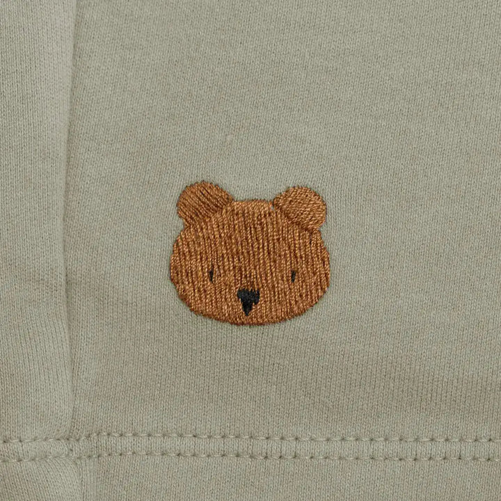 Donsje Ithri Shorts Bear dusty green Detailaufnahme aufgesticktes Donsje Bärengesicht auf grau-grünem Baumwollstoff