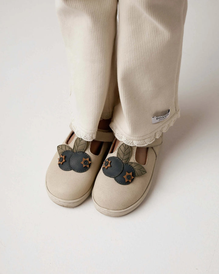 Donsje Jentje trousers macaroon getragen von einem Mädchen vor weißem Hintergrund, Nahaufnahme Füße und ausgestelltes Bein mit Spitzen-Saum 