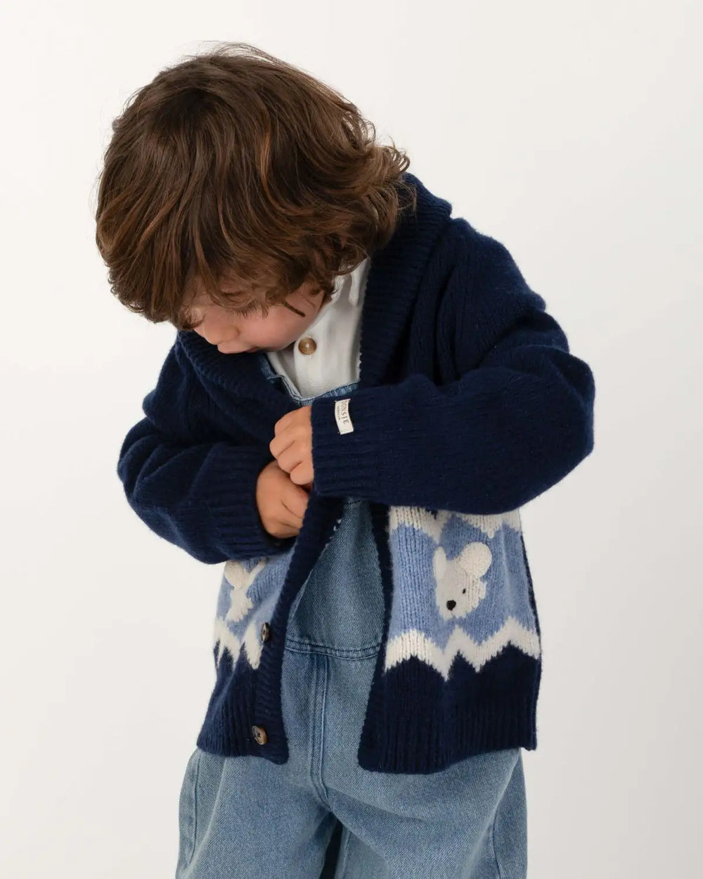 Donsje Kwinten Merino Wool Cardigan Polar Bears navy blue getragen von einem kleinen Jungen vor einem weißen Hintergrund stehend, Ansicht von vorne. 