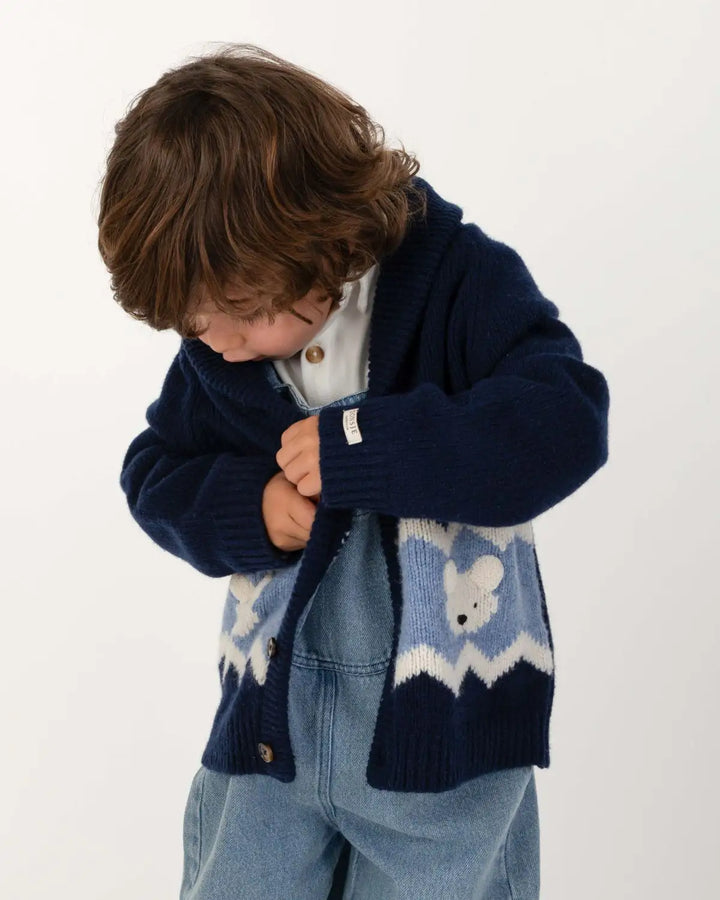 Donsje Kwinten Merino Wool Cardigan Polar Bears navy blue getragen von einem kleinen Jungen vor einem weißen Hintergrund stehend, Ansicht von vorne. 