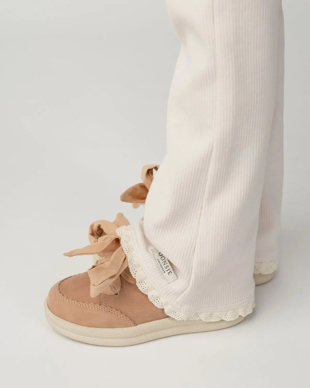 Donsje Lexley Sneakers coral betting leather  getragen von einem Mädchen mit Fokus auf dem Schuh vor weißem Hintergrund und kombiniert mit einer Leggings mit ausgestelltem Bein