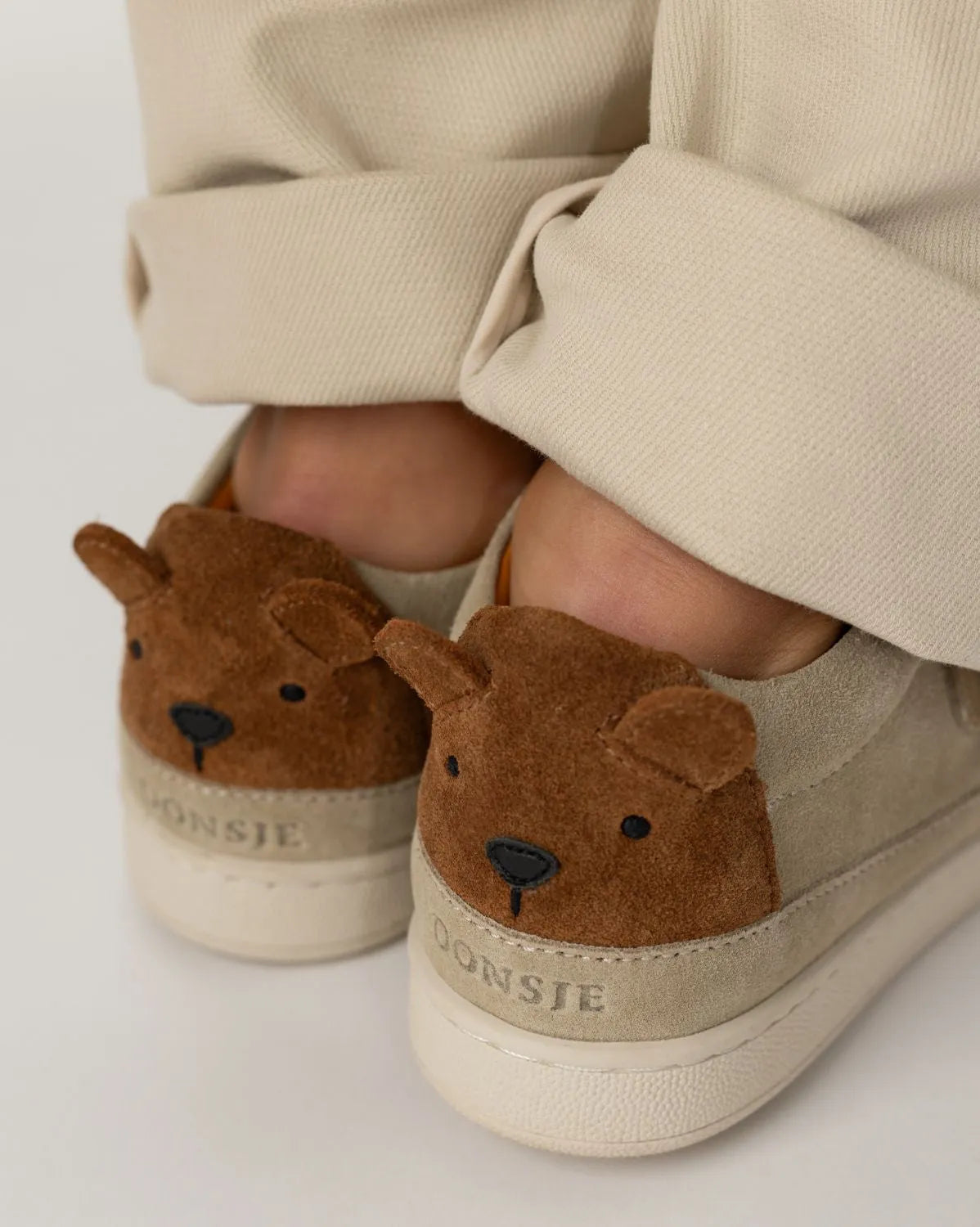 Donsje Rinou Sneakers Bear taupe suede getragen von einem Kind, Fokus auf den beiden Bärengesichtern an der Ferse