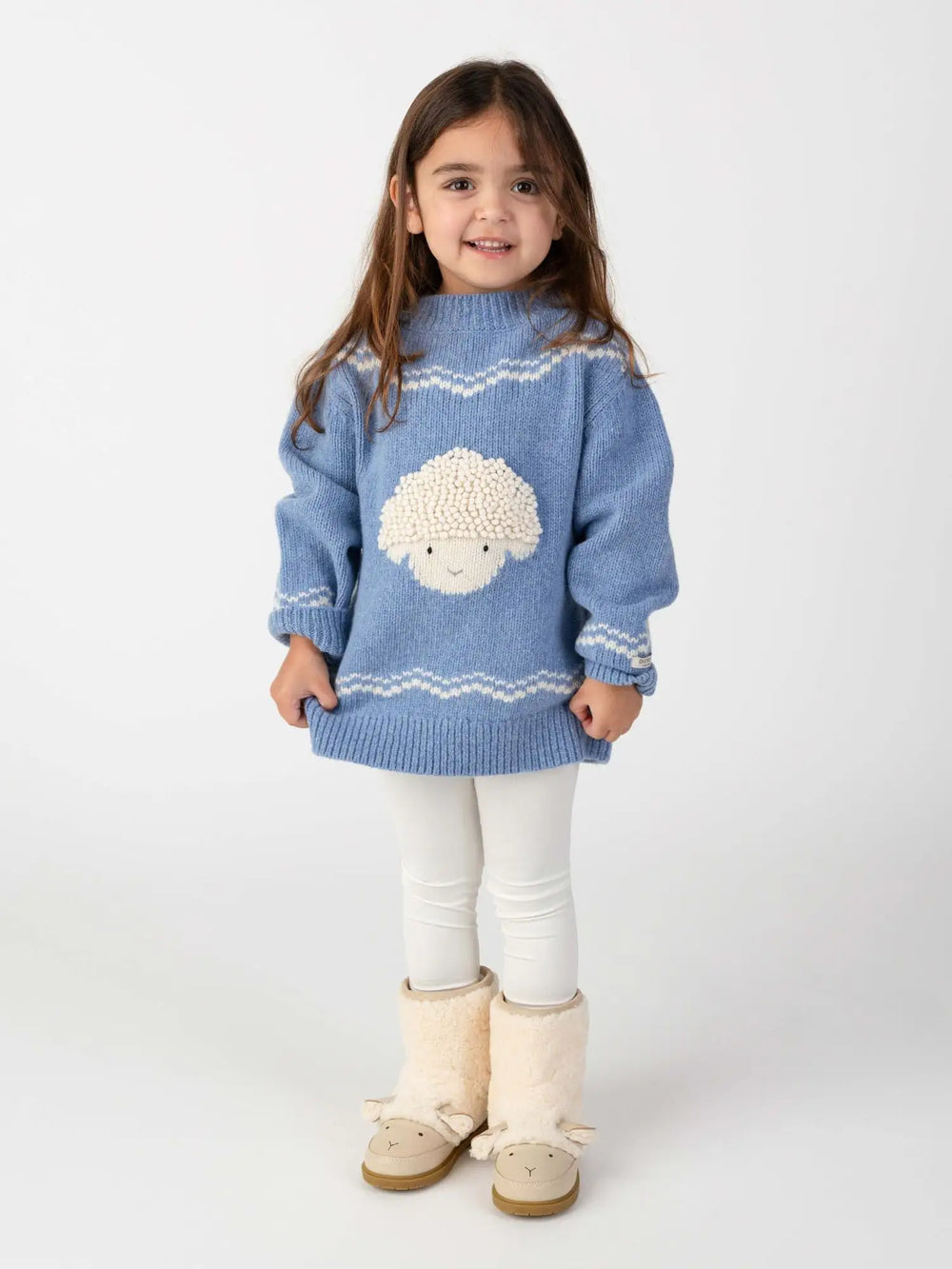 Donsje Selwyn Merino Wool Sweater Lammy vintage blue melange getragen von einem Mädchen vor einem weißen Hintergrund stehend, Ansicht von vorne. 