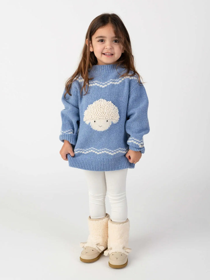 Donsje Selwyn Merino Wool Sweater Lammy vintage blue melange getragen von einem Mädchen vor einem weißen Hintergrund stehend, Ansicht von vorne. 