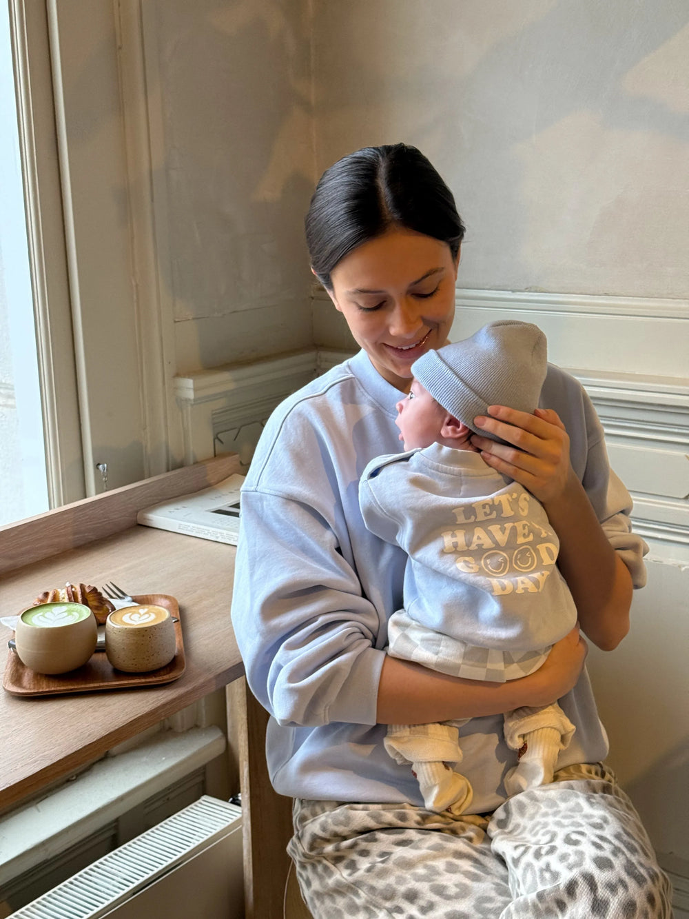 Famvibes GOOD DAY Sweatshirt Baby pastell-blue getragen von einem Neugeborenen auf dem Arm seiner Mutter