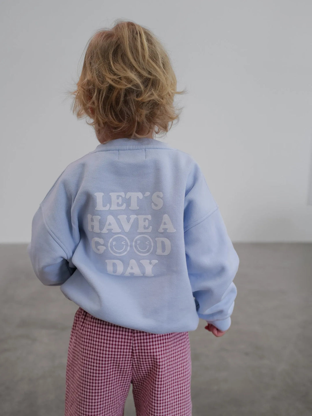 Famvibes GOOD DAY Sweatshirt Baby pastell-blue getragen von einem kleinen Kind, Ansicht von hinten mit Blick auf Print