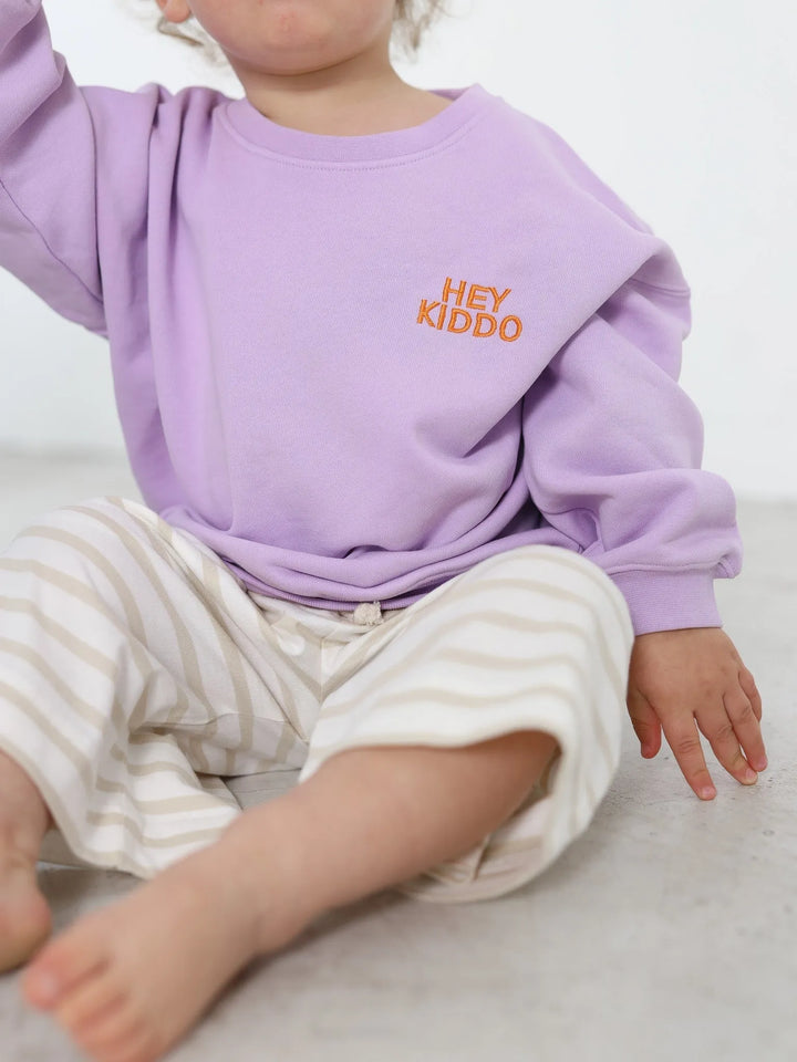 lilafarbenes Sweatshirt für Kinder mit orangefarbenem Schriftzug Hey Kiddo