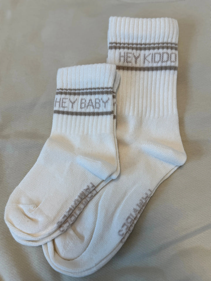 weiße Socken für Kinder aus Baumwolle mit taupefarbenem Schriftzug Hey Kiddo