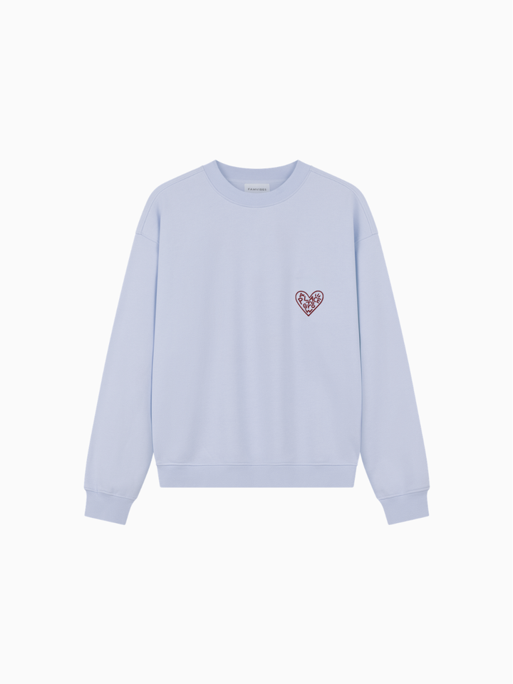 hellblaues Sweatshirt Erwachsene aus 100% Baumwolle mit einem kleinen aufgestickten Herzen in rot auf Höhe der linken Brust mit dem Schriftzug "Place To Grow". Auf der Rückseite befinden sich verschiedene Stickereien wie zum Beispiel ein Teddybär, ein Marmeladenglas, Blätter. Produktbild, Ansicht von vorne. 