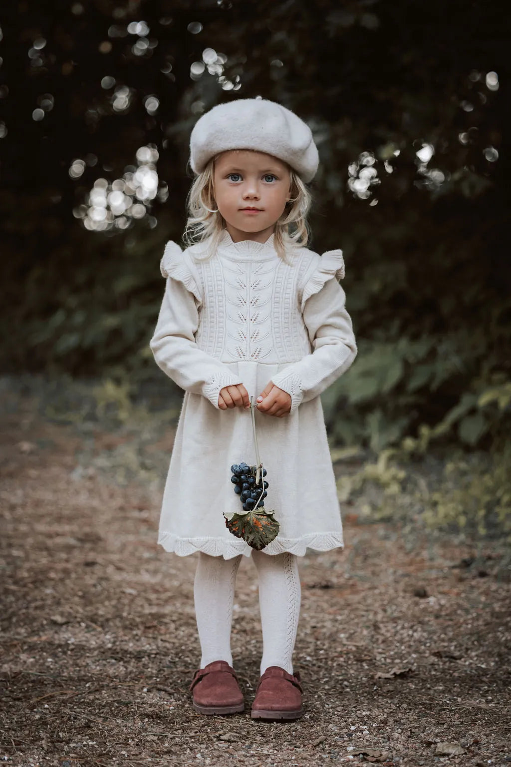 cremefarbenes knielanges Kleid mit langen Ärmeln für Mädchen aus Ecovero Viskose mit romantischen Details am Saum und an den Schultern. 