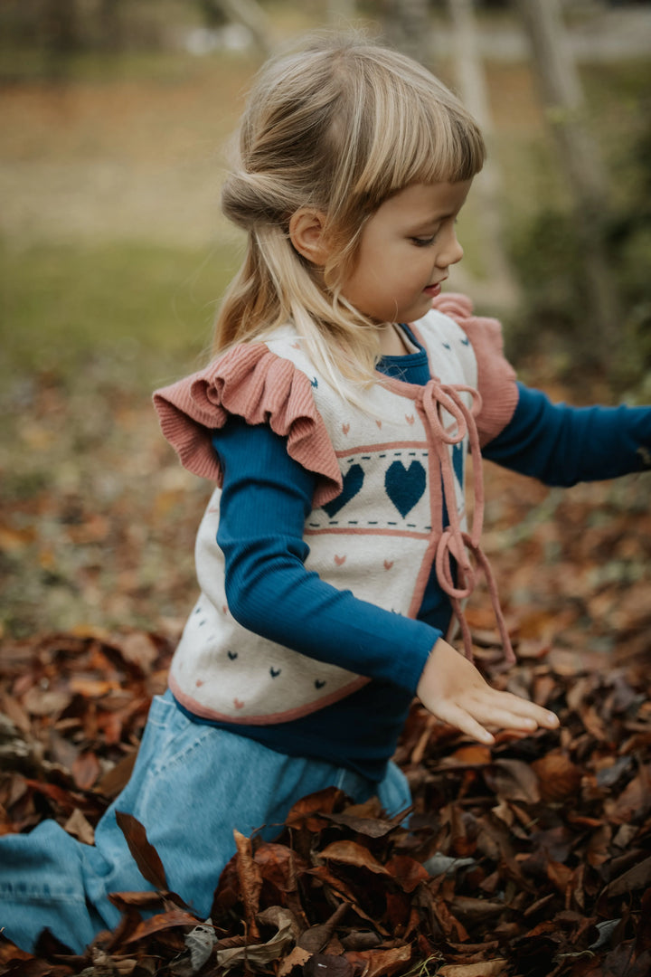 Strickweste für Mädchen aus Bio-Baumwolle mit zwei Bindebändern vorne in cremefarben und einem Herzmuster in blau und rosa