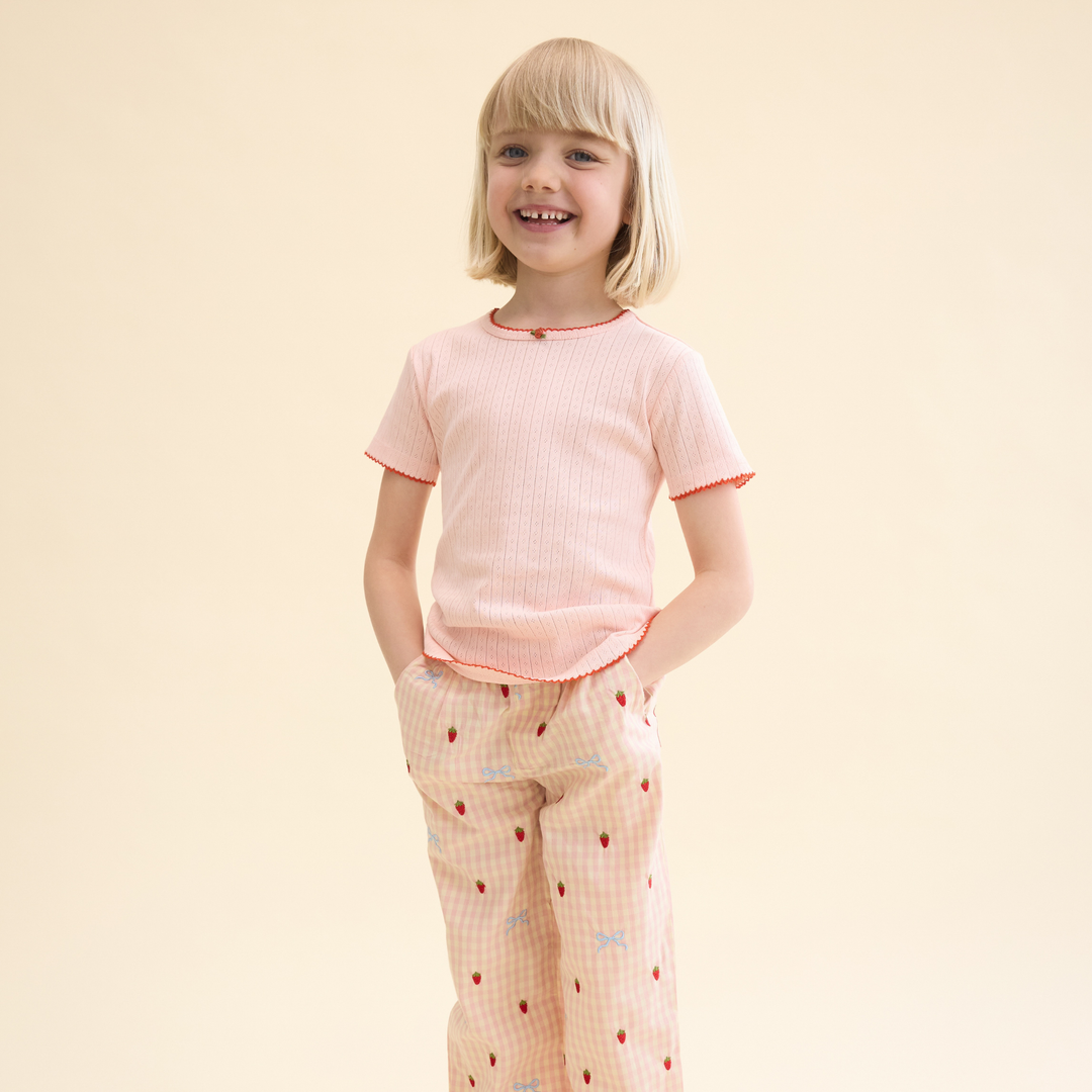 weiches T-Shirt auf Pointelle-Jersey mit einer kleinen Satin-Rose am Rundhalsausschnitt auf der Vorderseite und mit Spitzensaum, getragen von einem Mädchen, Ansicht von vorne