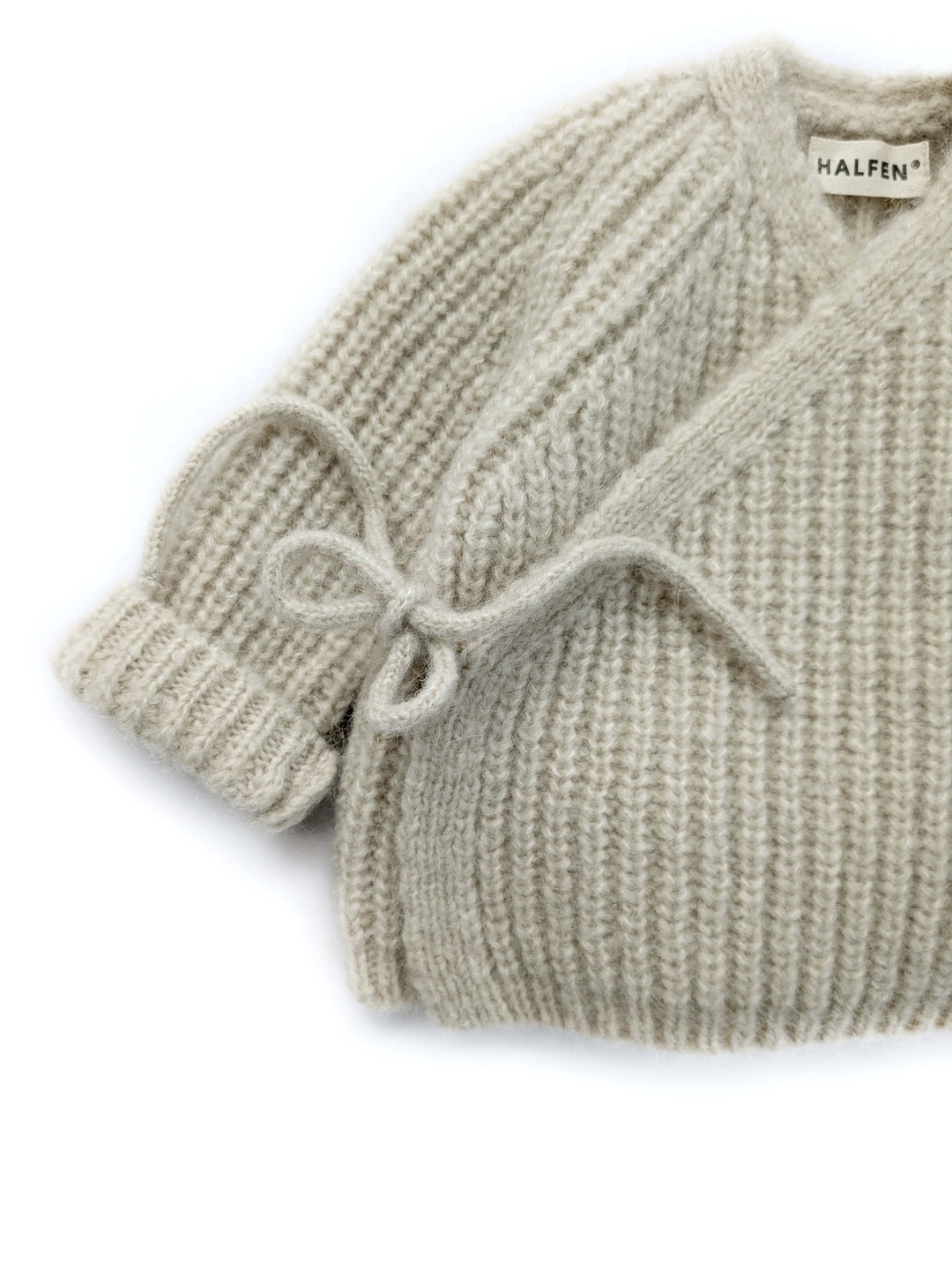 Halfen Alpaka Grobstrickjacke beige Detailansicht Bindeband und asymmetrischer Verschluss. 