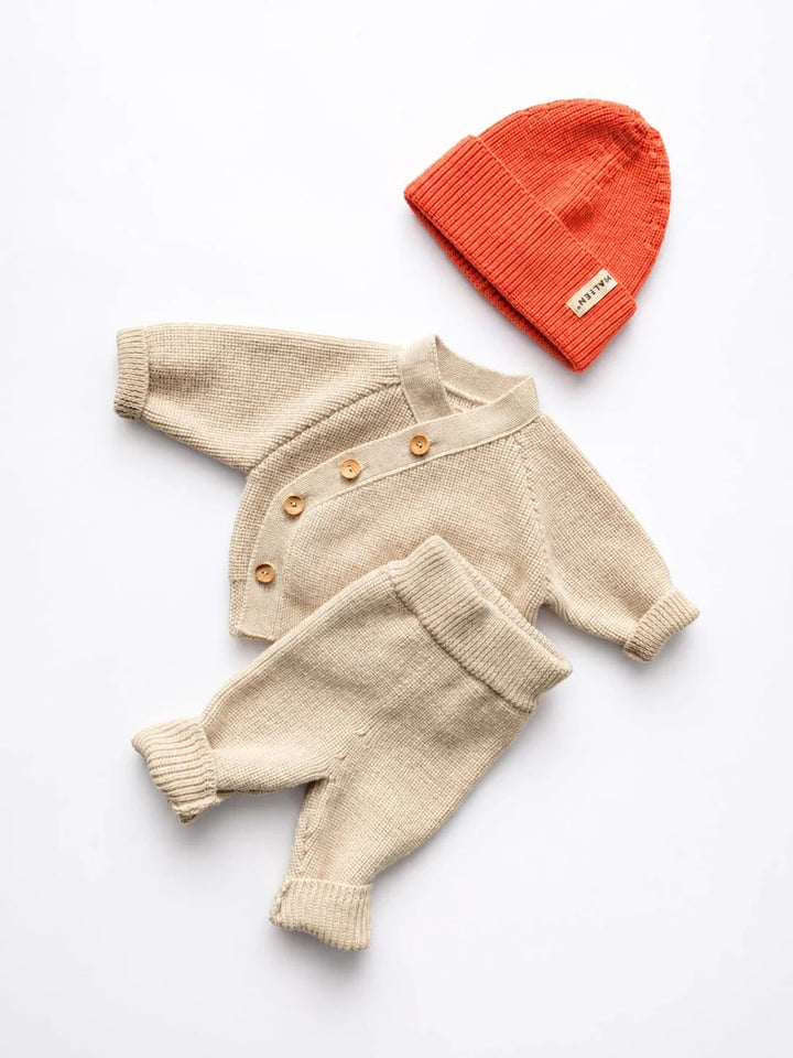 Halfen Grobstrick-Schlüttli zum Knöpfen natur Produktbild, kobiniert mit der Strick-Beanie Merino und der Grobstrick-Leggings in natur. 