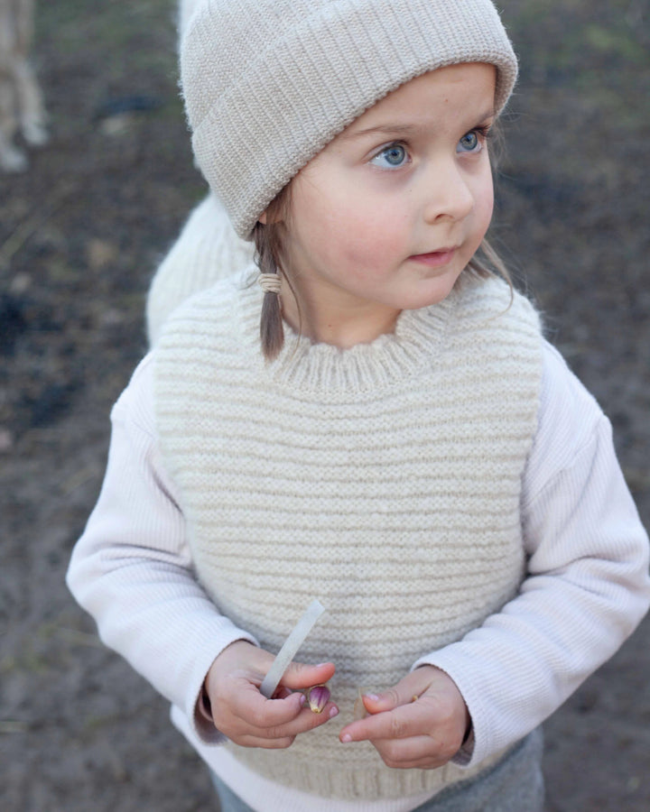Halfen Struktur Pullunder Alpaca K7S35 beige getragen von einem kleinen Mädchen in der Natur, Ansicht von vorne oben. 