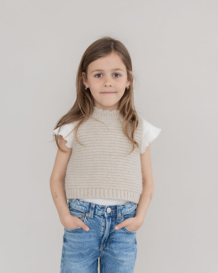 Halfen Struktur Pullunder Alpaca K7S35 beige getragen von einem Mädchen vor einer Leinwand stehend, Ansicht von vorne. 