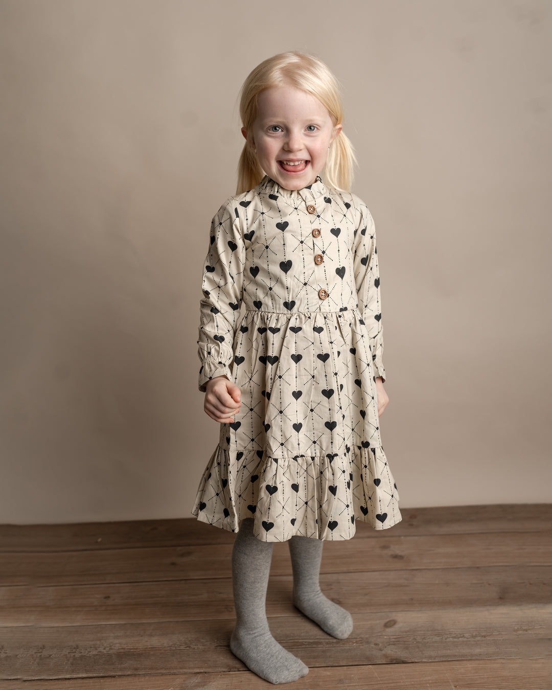 cremefarbenes Kleid für Mädchen aus Baumwolle mit dunkelblauem Herz-Print, Knopfleiste, Rüschen am Kragen und leicht ausgestelltem Saum