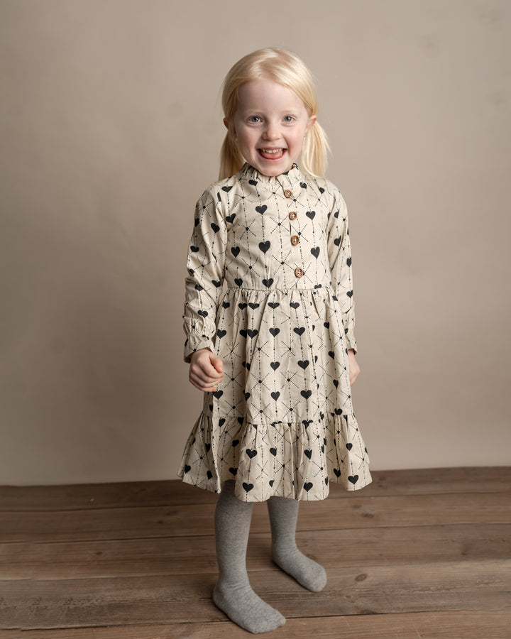 cremefarbenes Kleid für Mädchen aus Baumwolle mit dunkelblauem Herz-Print, Knopfleiste, Rüschen am Kragen und leicht ausgestelltem Saum