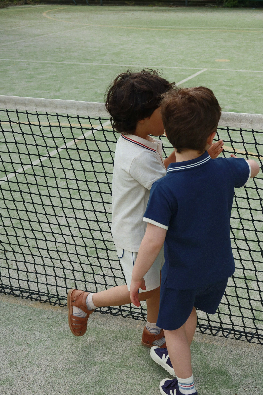 Konges Sloejd Florian Shorts spellbound getragen von einem Jungen auf einem Tennisplatz, Ansicht von hinten 