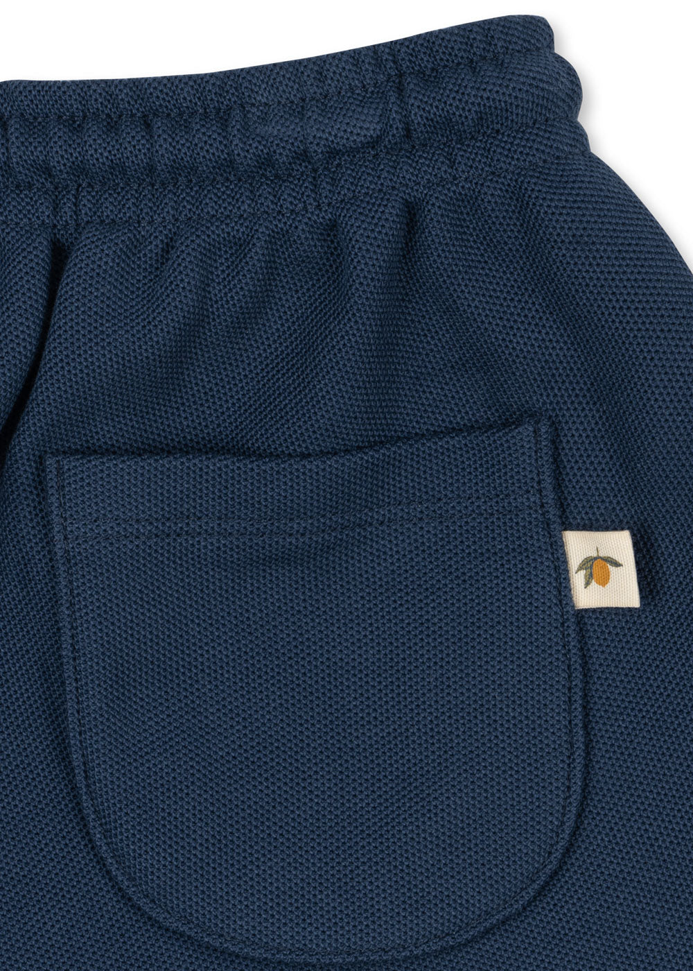 Konges Sloejd Florian Shorts spellbound Detailansicht Gesäßtasche mit kleinem angenähten Label, auf dem sich eine Zitrone befindet