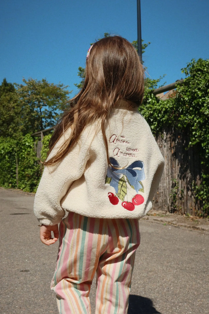 Konges Sloejd Frankie Pants miami stripe getragen von einem Mädchen, das auf einer Straße läuft. Ansicht von hinten. 