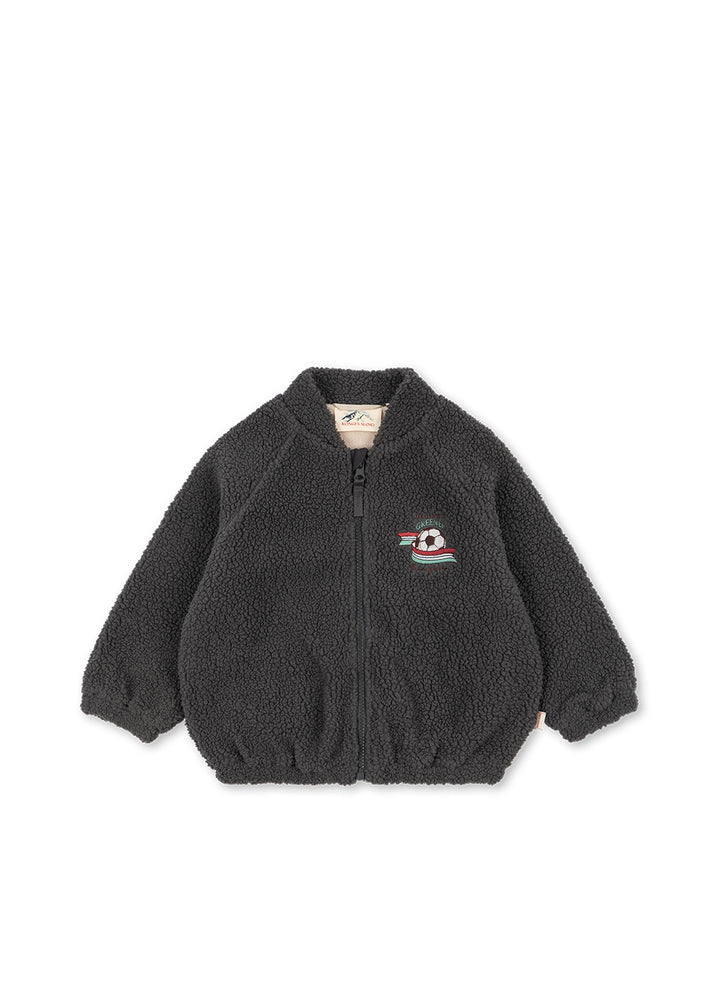 Fleecejacke aus dunkelgrauem Teddyfleece, auf deren Rückseite sich ein großes, gesticktes Motiv mit einem Fußball und einem Band in Rot, Weiß, Grün und Blau befindet. Mit Bomberjacken-Kragen, durchgehendem Reißverschluss und Gummibund an den Ärmelabschlüssen und am Saum. Produktbild, Ansicht von vorne. 