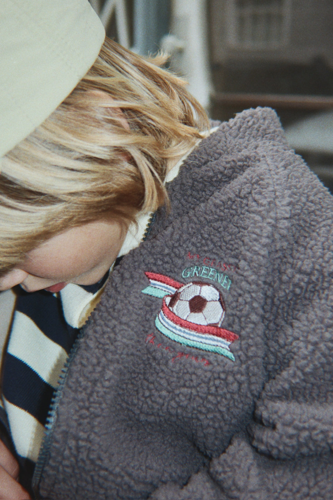 Konges Sloejd Jody Bomber Jacket GRS magnet getragen von einem Jungen, Detailansicht kleiner aufgestickter Fußball auf der Vorderseite auf Höhe der linken Brust. 