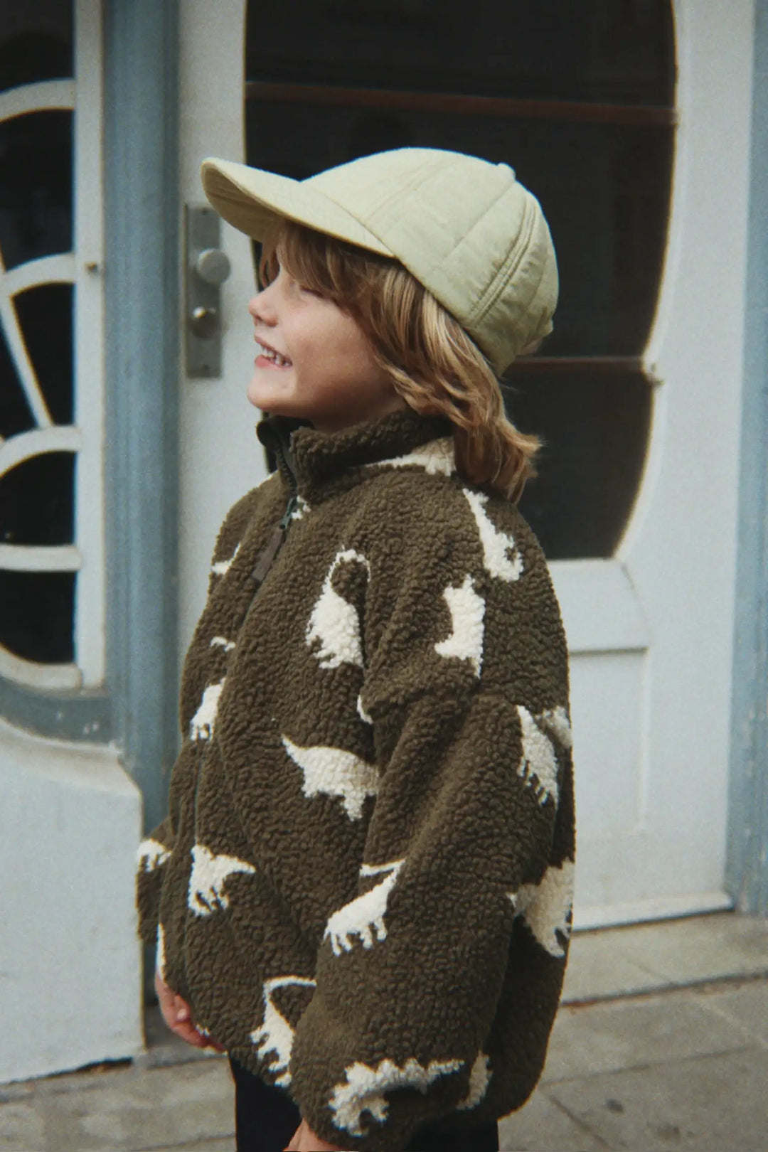 Konges Sloejd Jody Teddy Jacket GRS dino silhouette getragen von einem kleinen Kind, Ansicht von der Seite. 