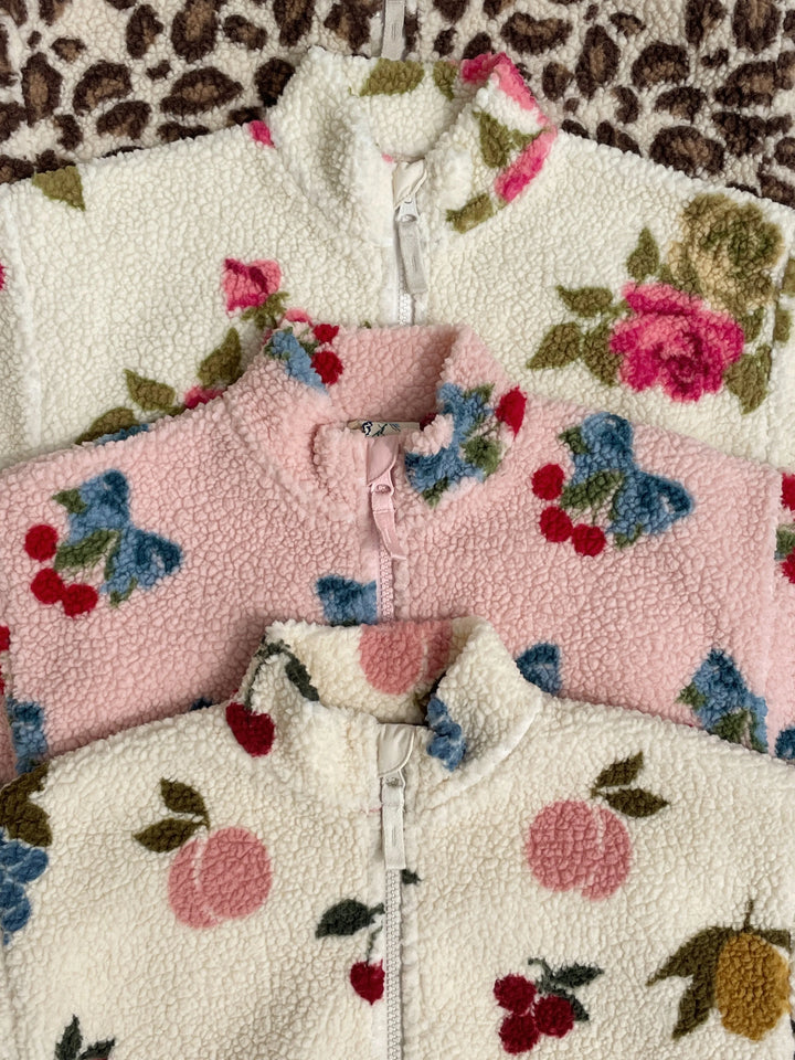 Jody Teddyjacke von Konges Sloejd Farbe amarena rose und leo Nahaufnahme Kragen, liegend zwischen zwei anderen, anders gemusterten Fleecejacken