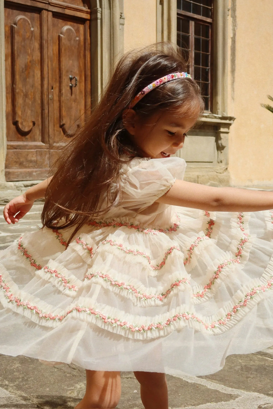 Konges Sloejd Joelle Dress buttercream getragen von einem Mädchen auf einer italienischen Piazza, dass sich schnell dreht, sodass der Rock schwingt