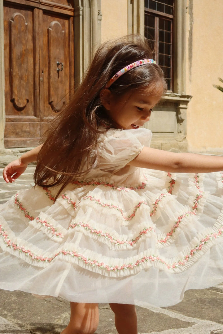 Konges Sloejd Joelle Dress buttercream getragen von einem Mädchen auf einer italienischen Piazza, dass sich schnell dreht, sodass der Rock schwingt