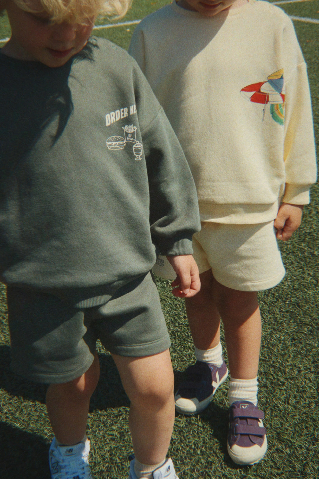 Konges Sloejd Lou Sweat Shirt OCS cilantro getragen von einem Jungen auf einem Sportplatz, Ansicht von vorne, kombiniert mit der Konges Sloejd Lou Sweat Shorts OCS cilantro