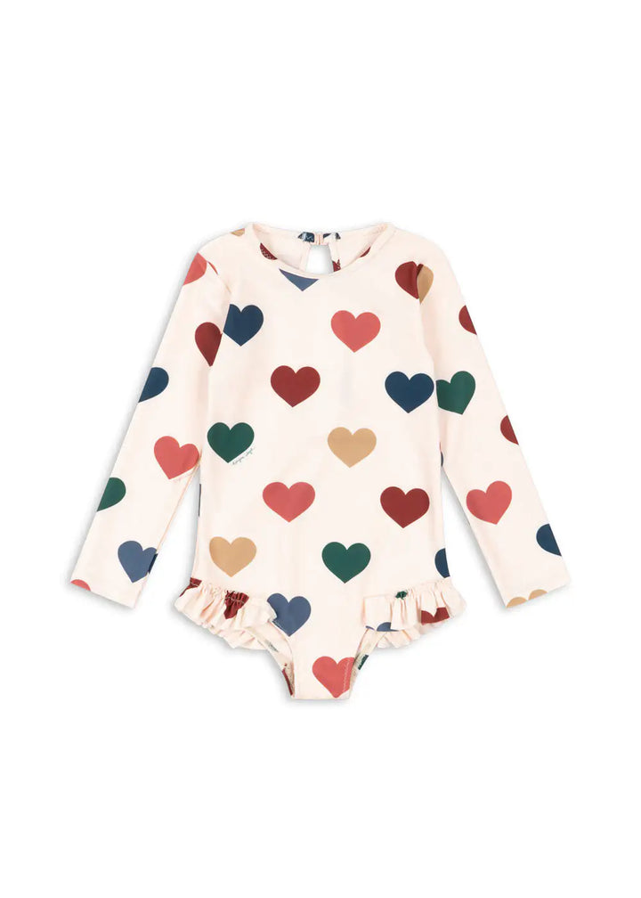 cremefarbener, langärmeliger Badeanzug für Mädchen mit buntem Herz-Allover-Print, Rundhalsausschnitt und Rüschen an den Beinausschnitten. Produktbild, Ansicht von vorne. 