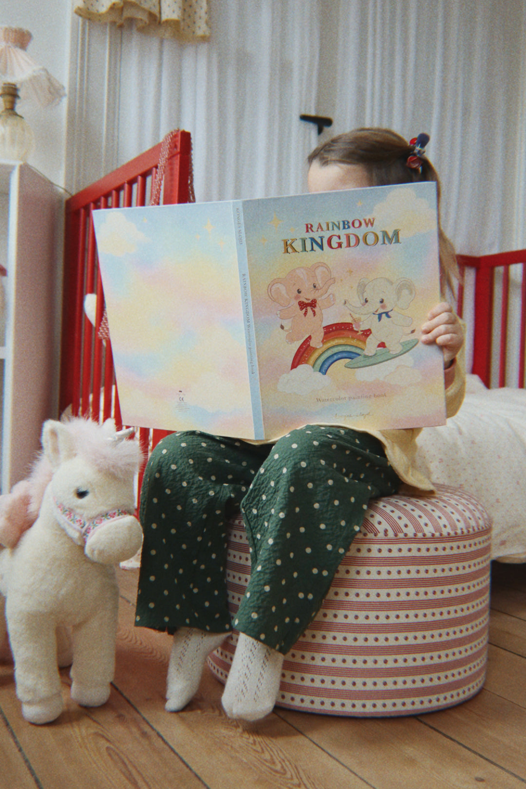 Konges Sloejd Starlight Unicorn off white neben einem Hocker stehend, Ansicht von vorne. 