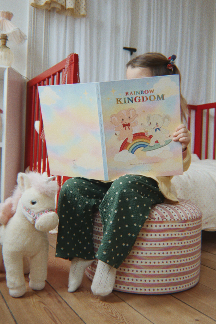 Konges Sloejd Starlight Unicorn off white neben einem Hocker stehend, Ansicht von vorne. 
