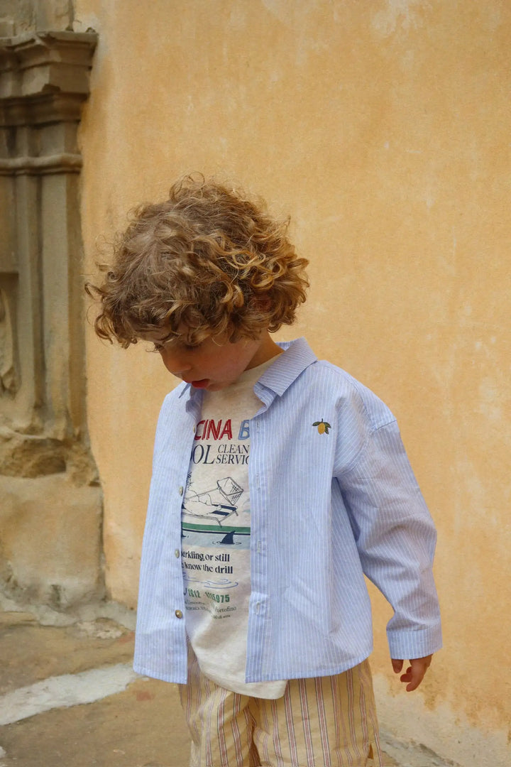 Konges Sloejd Wes Shirt GOTS blue stripe getragen von einem männlichen Kleinkind Ansicht von vorne mit geöffneter Knopfleiste und einem passenden T-Shirt darunter