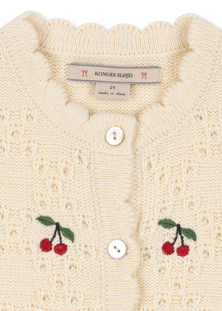 Konges Slojd Cocolo Cardigan buttercream Produktbild, Detailansicht aufgestickte Kirschen und Wellenkante am Rundhalsausschnitt. 